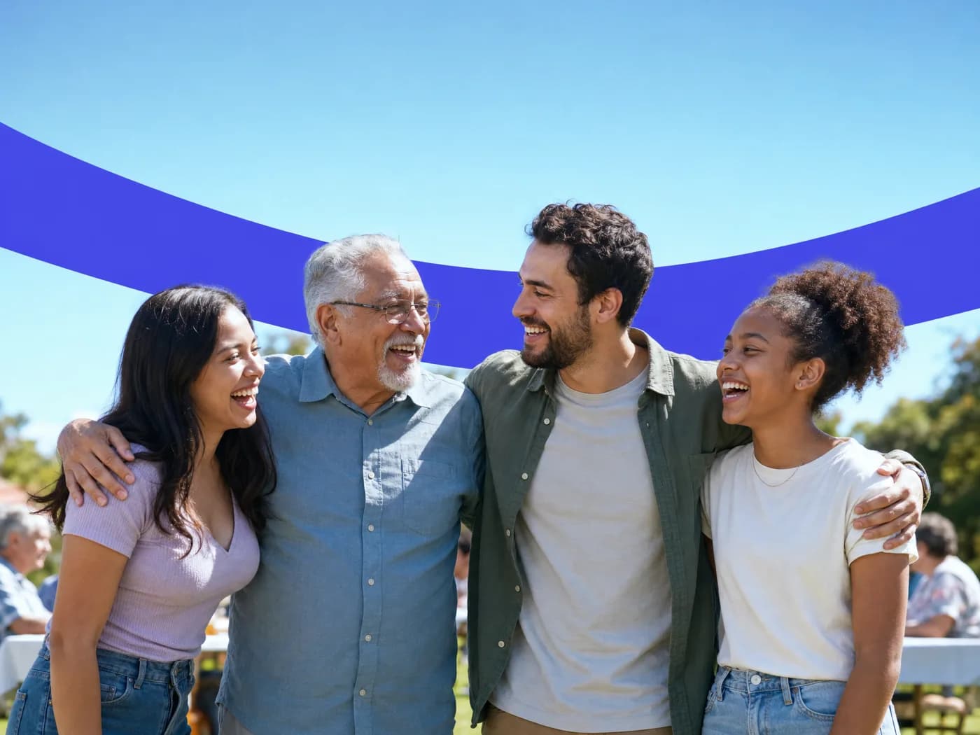 Four friends of different ages laughing together at an outdoor community picnic